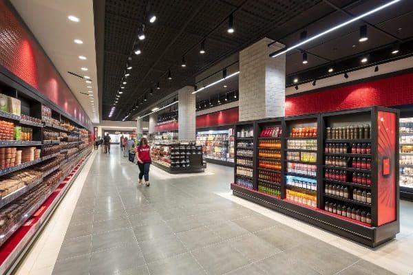 Wide grocery store aisle with modern lighting and fully stocked shelves on both sides